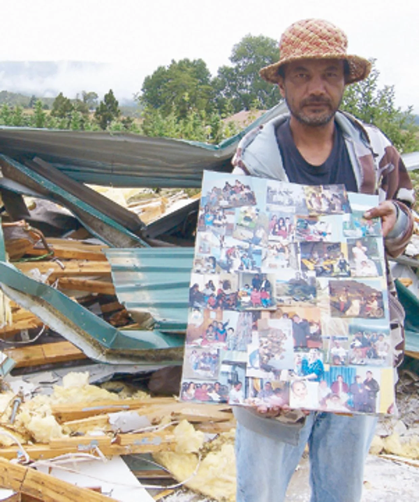 Man before remains of his mother’s house, bulldozed by bank.